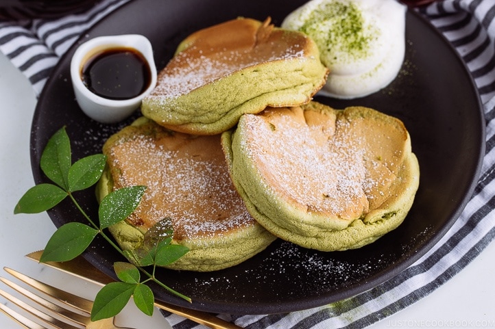 Matcha Souffle Pancakes topped with powder sugar and fresh whipped cream.