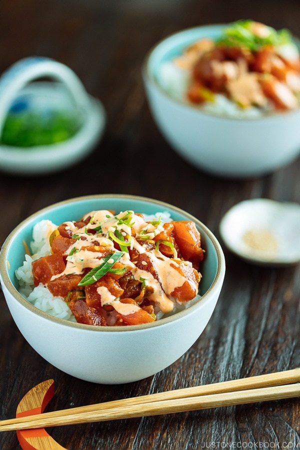 Spicy Tuna served over bed of rice in a bowl, drizzled with spicy mayo and garnished with scallion on top.