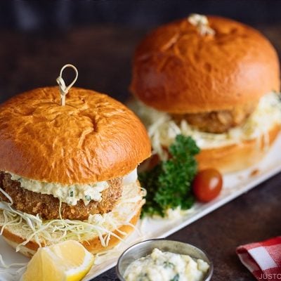 Menchi Katsu Sandwich is a ground meat patty coated with crispy panko and deep fried into golden brown. It is then topped with thinly sliced cabbage and homemade tartar sauce, and sandwiched in soft brioche buns.