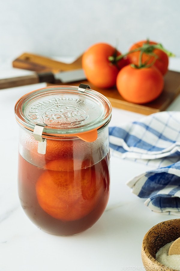 A glass jar containing pickled tomatoes.