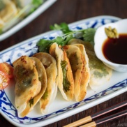 A plate containing chicken shiso gyoza and a small bowl of ponzu and yuzu kosho.