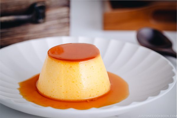 A white plate containing Kabocha-flavored Flan with caramel sauce on top.