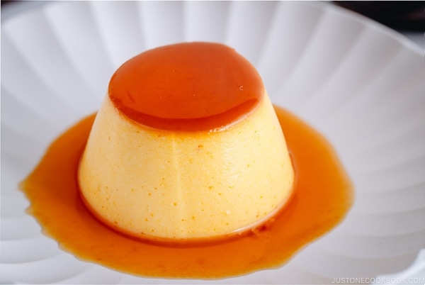 A white plate containing Kabocha-flavored Flan with caramel sauce on top.