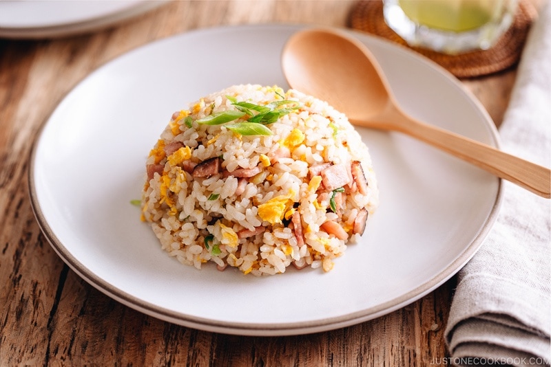 Fried rice with egg, ham, and green onion on a white plate.