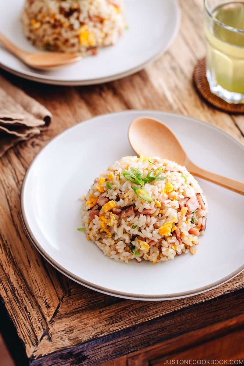 Fried rice with egg, ham, and green onion on a white plate.