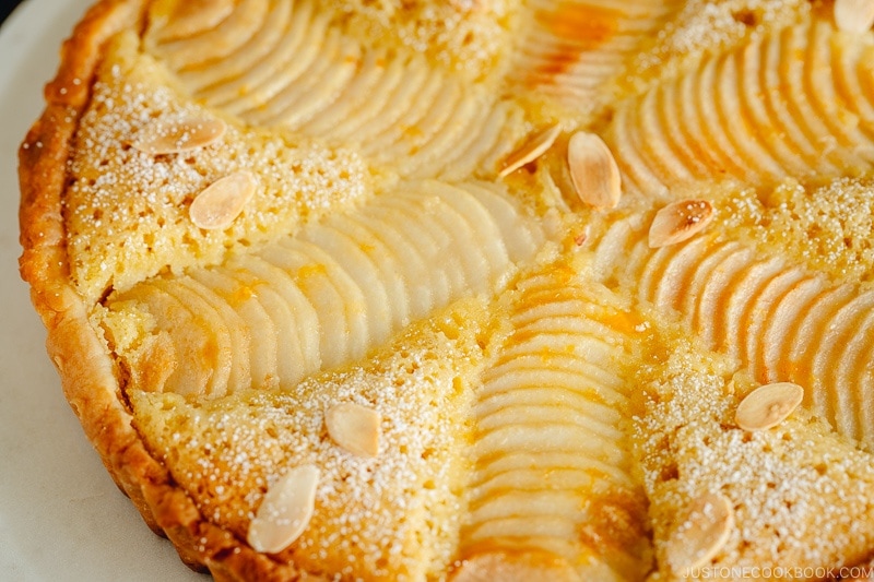 Pear and Almond Tart (Pear Frangipane Tart) dusted with powdered sugar and sprinkled with toasted almond slices.