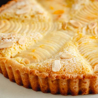 Pear and Almond Tart (Pear Frangipane Tart) dusted with powdered sugar and sprinkled with toasted almond slices.