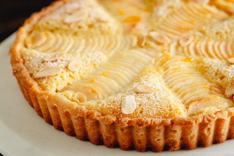 Pear and Almond Tart (Pear Frangipane Tart) dusted with powdered sugar and sprinkled with toasted almond slices.