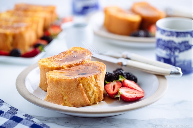 A plate containing French toast, strawberries, and black berries.