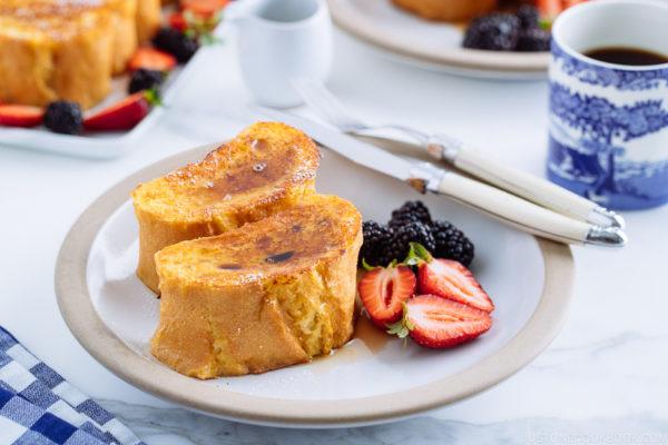 A plate containing French toast, strawberries, and black berries.