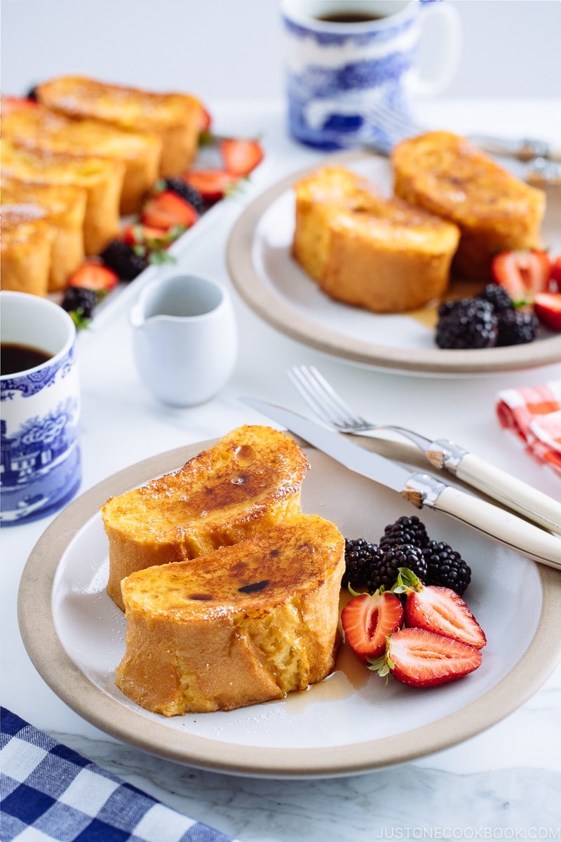 A plate containing French toast, strawberries, and black berries.