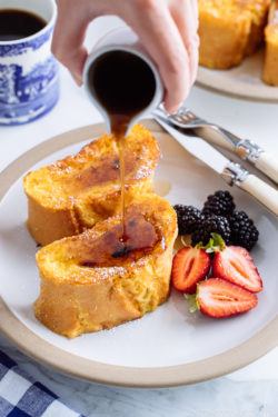 A plate containing French toast, strawberries, and black berries.