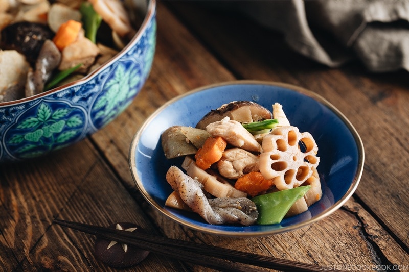 A blue Japanese bowl containing Nishime, simmered vegetables and chicken.