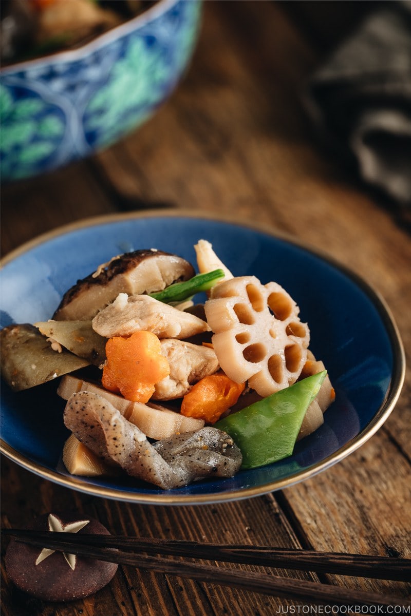 A blue Japanese bowl containing Nishime, simmered vegetables and chicken.