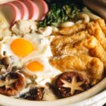 A donabe containing udon noodles, chicken, fish cakes, deep fried tofu, mushrooms, and leeks in a hearty miso broth.