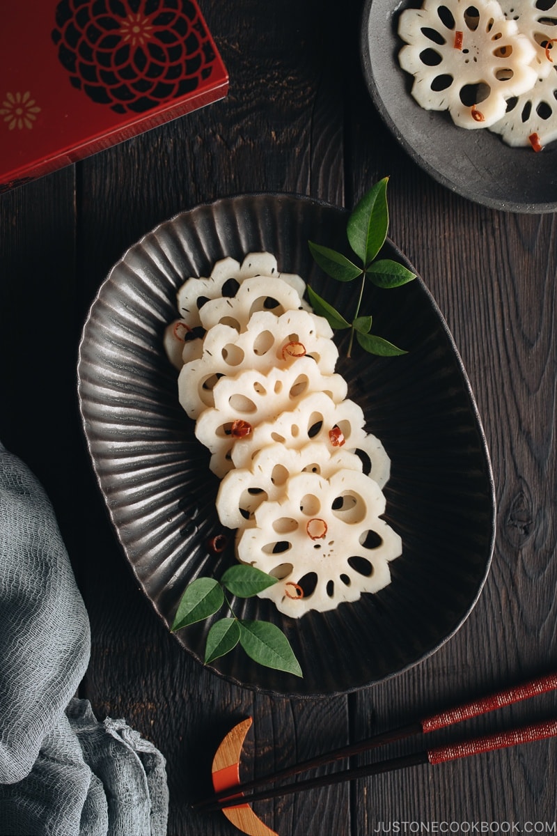 A black plate containing Pickled Lotus Root (Su Renkon), garnished with chopped red chili pepper.