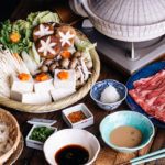 Tablesetup for shabu shabu - donabe hot pot, vegetables, meat, udon, and dipping sauces.