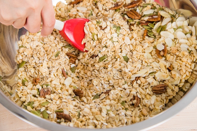 Mixing granola and nuts in a metal mixing bowl