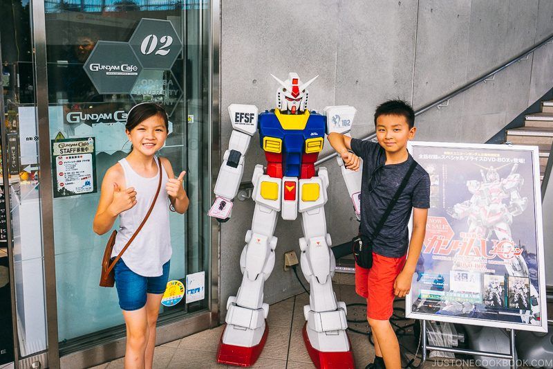 children next to small Gundam Statue at Gundam Cafe - Tokyo Odaiba Travel Guide | www.justonecookbook.com