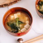 Japanese wooden bowls containing vegan miso soup with tofu and seaweed.