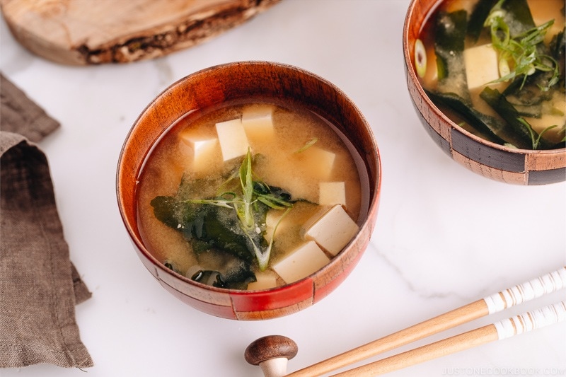 Japanese wooden bowls containing vegan miso soup with tofu and seaweed.