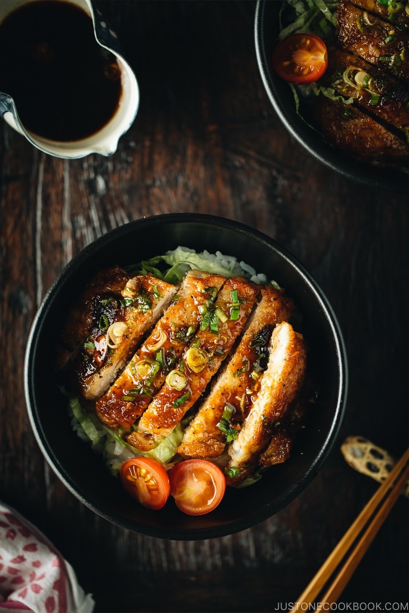 A black bowl containing Teriyaki Pork over steamed rice drizzled with homemade teriyaki glaze.