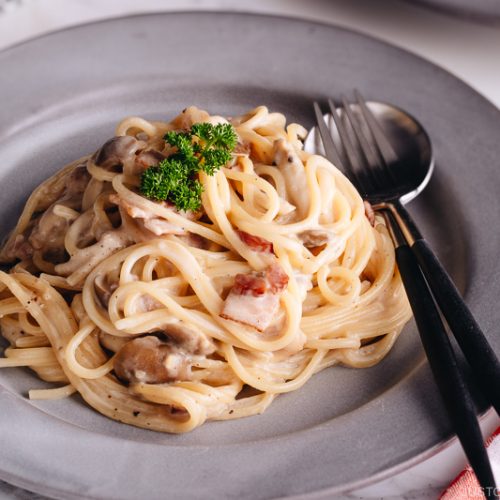 Creamy Mushroom and Bacon Pasta on a grey plate.