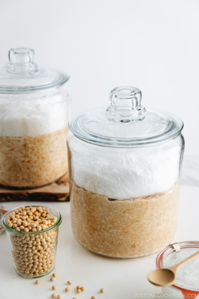 Homemade miso is in the making; soybeans, salt, and koji mixture in a glass jar.