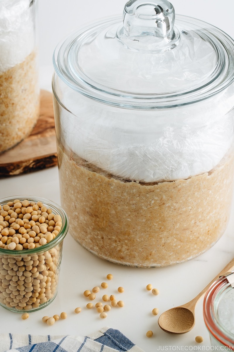 Homemade miso is in the making; soybeans, salt, and koji mixture in a glass jar.