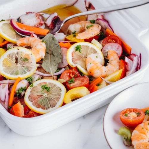 Seafood salad with vinaigrette in the white baking dish.