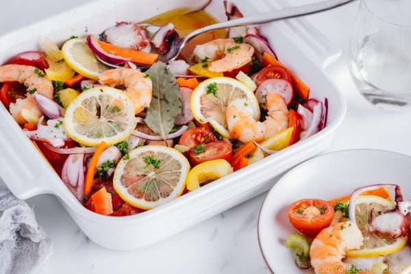 Seafood salad with vinaigrette in the white baking dish.