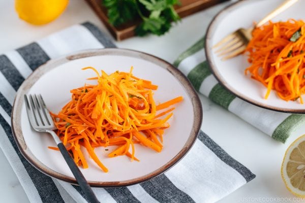 Carrot salad on a white plate with gray rim.