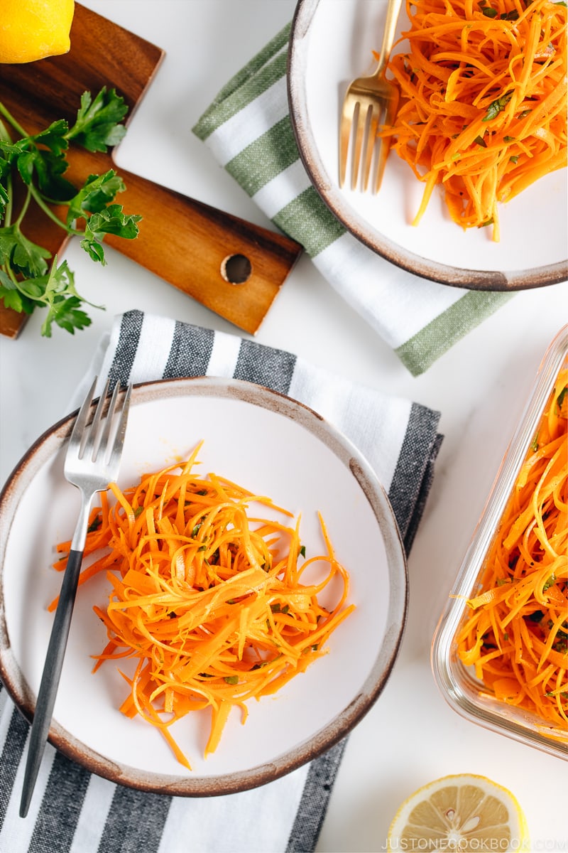 Carrot salad on a white plate with gray rim.