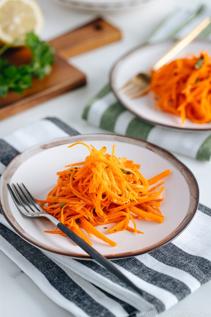 Carrot salad on a white plate with gray rim.