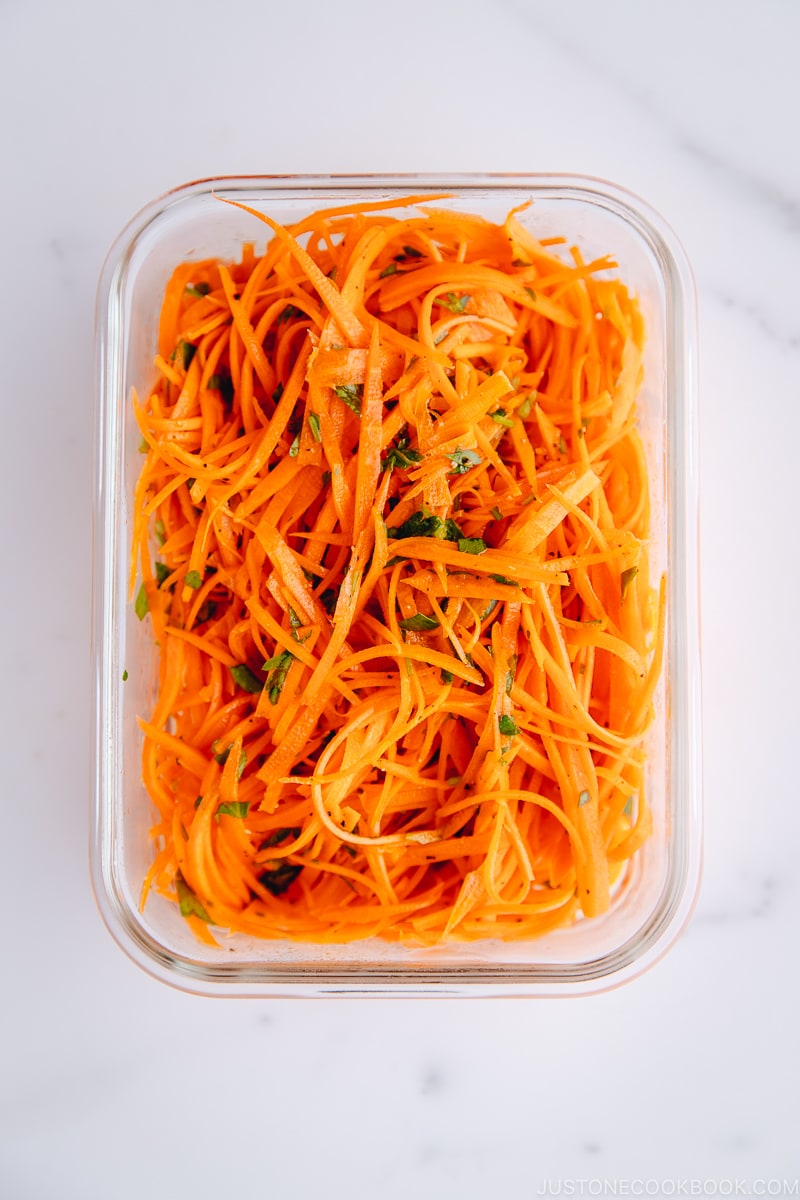 Carrot salad in a glass meal prep container.