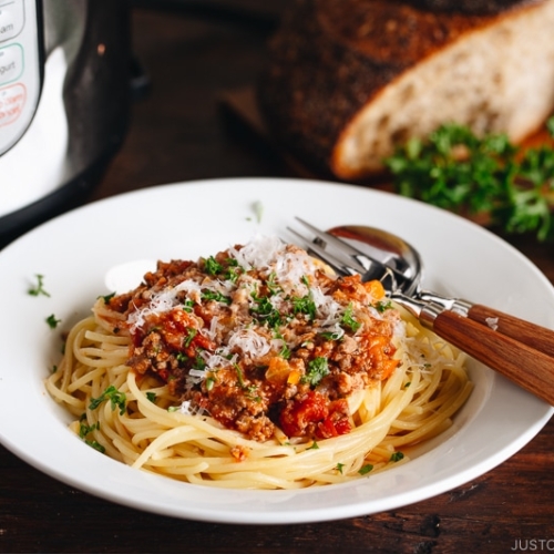 Spaghetti Bolognese on a white plate next to the Instant Pot.