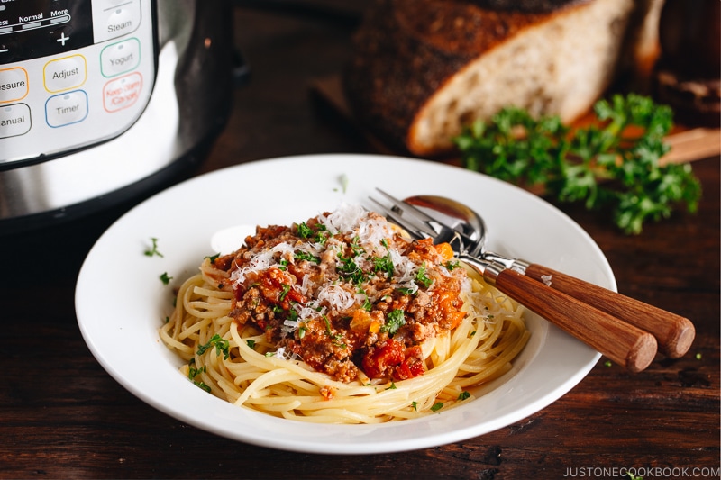 Spaghetti Bolognese on a white plate next to the Instant Pot.