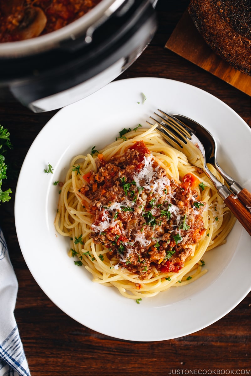 Spaghetti Bolognese on a white plate next to the Instant Pot.