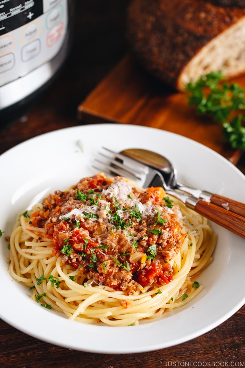 Spaghetti Bolognese on a white plate next to the Instant Pot.