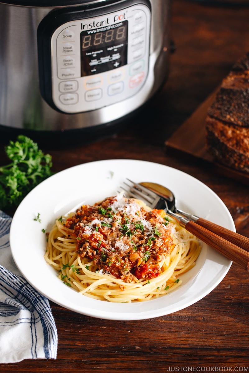 Spaghetti Bolognese on a white plate next to the Instant Pot.