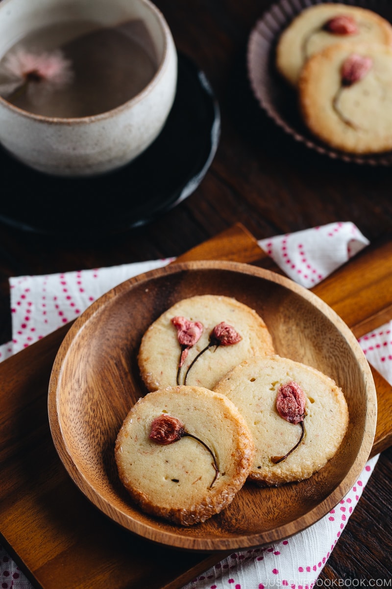 Cherry blossom cookies on a wooden plate.