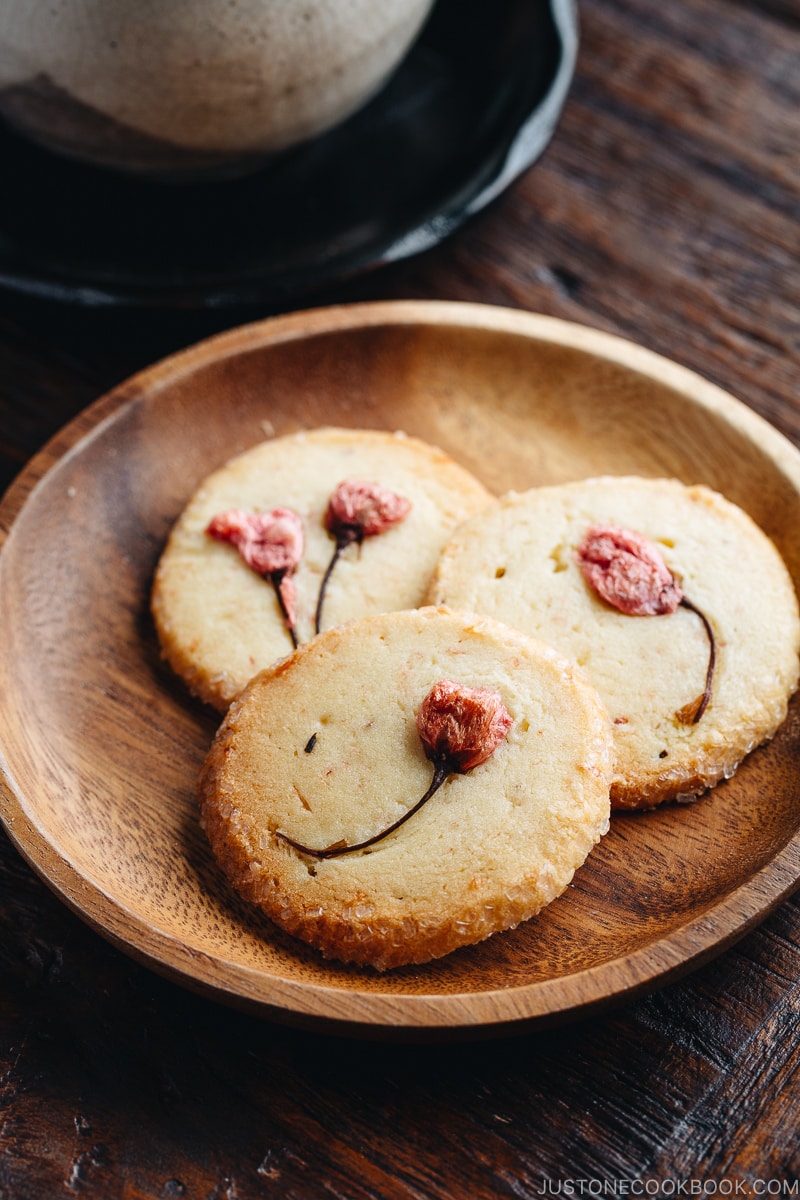 Cherry blossom cookies on a wooden plate.