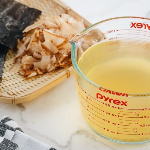 Awase Dashi in a measuring cup, and kombu and katsuobushi on a bamboo basket.