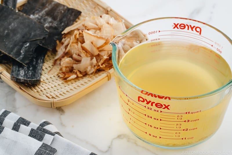 Awase Dashi in a measuring cup, and kombu and katsuobushi on a bamboo basket.