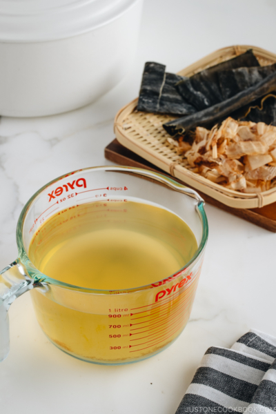 Awase Dashi in a measuring cup, and kombu and katsuobushi on a bamboo basket.