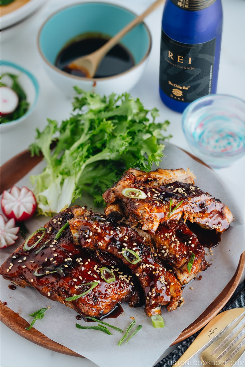 Sticky Asian Ribs on a white platter, topped with sprinkle of green onion.