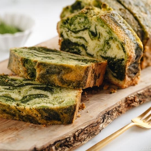 A few slices of matcha marble pound cake served on a wooden board.