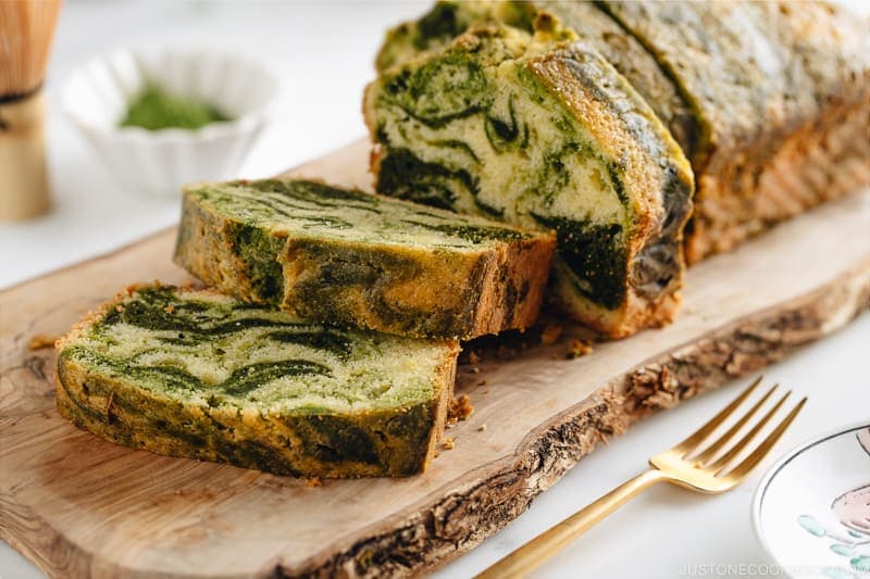 A few slices of matcha marble pound cake served on a wooden board.
