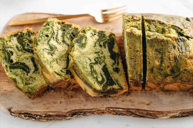 A few slices of matcha marble pound cake served on a wooden board.