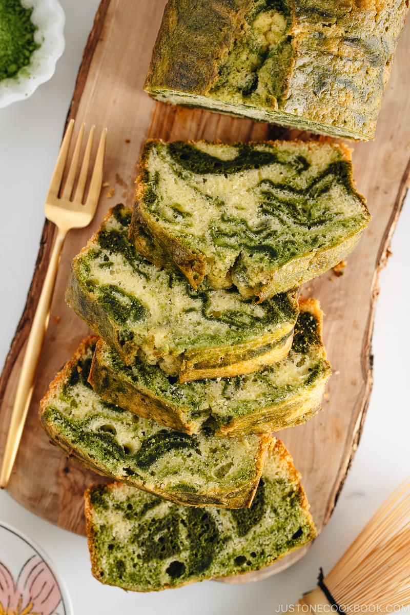 A few slices of matcha marble pound cake served on a wooden board.